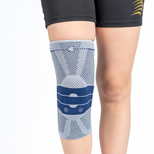 Ginocchiera Genutrain per stabilizzazione rotula grigio chiaro con inserti blu, indossata su gamba destra.