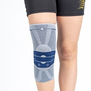 Ginocchiera Genutrain per stabilizzazione rotula grigio chiaro con inserti blu, indossata su gamba destra.